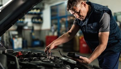 auto mechanic using diagnostic tool while checking car battery voltage workshop scaled.jpg